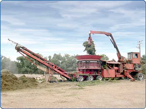 The arm of the loader brings the materials into the tub grinder to be ground down.