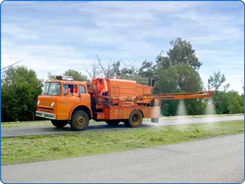 The arm of this truck is extending over the grass. Spraying herbicide onto the weeds kills the weed from the leaves to the root. The preemergent is applied to prevent the growth of weeds.